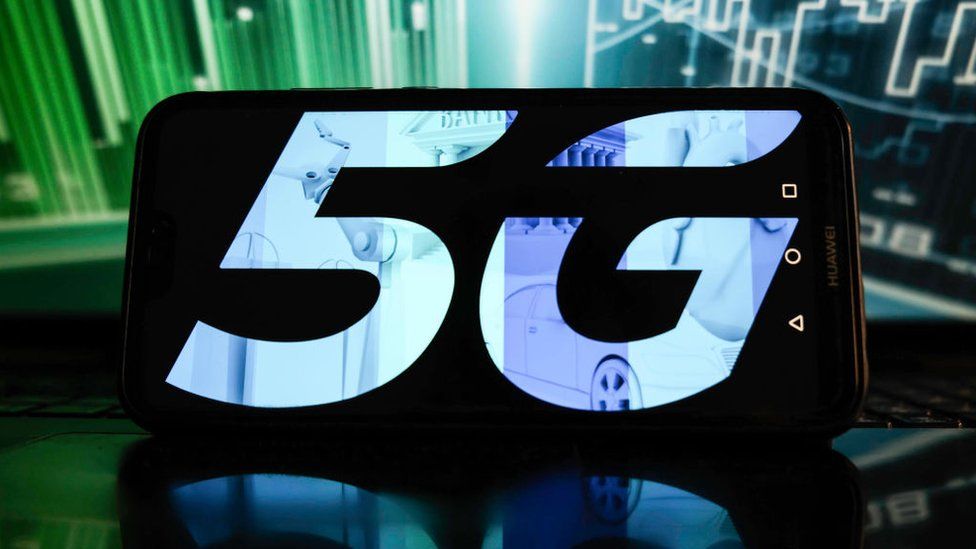 Esta ilustración fotográfica muestra un logotipo 5G en un teléfono inteligente con porcentajes bursátiles en el fondo.